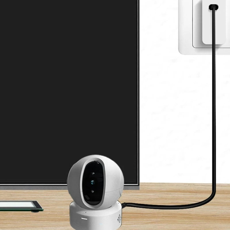 White security camera on a wooden surface with a television in the background