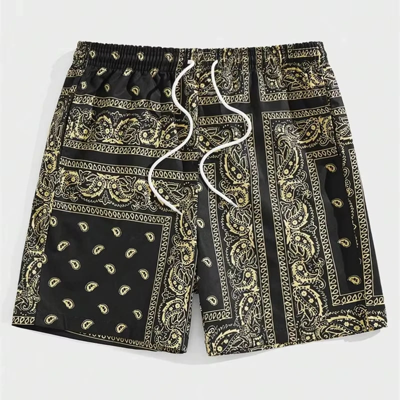Black and gold paisley patterned bandana shorts on a light grey background.