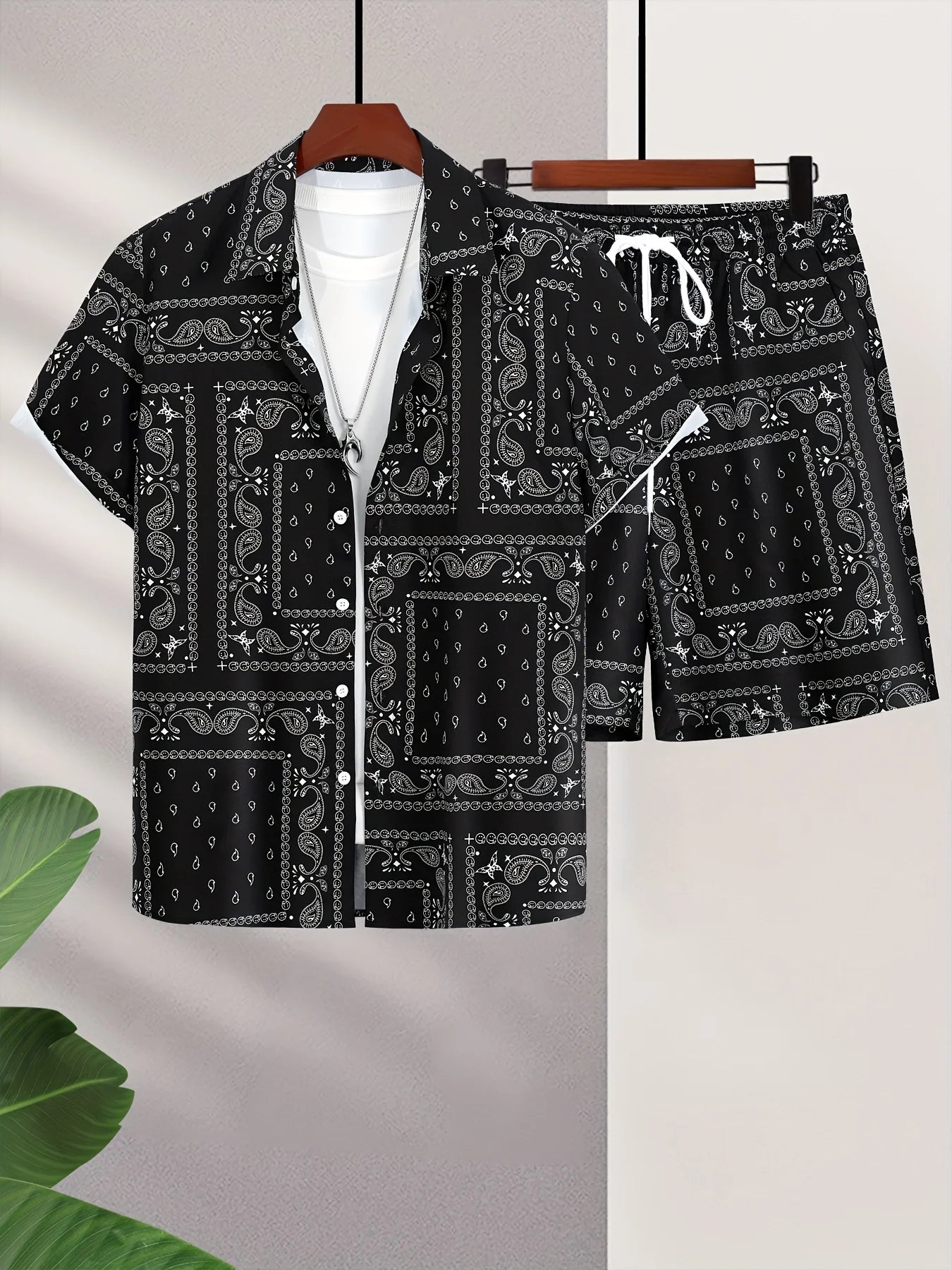 Black and white paisley patterned bandana shorts and short-sleeved button up shirt set combo unit on a light gray background.