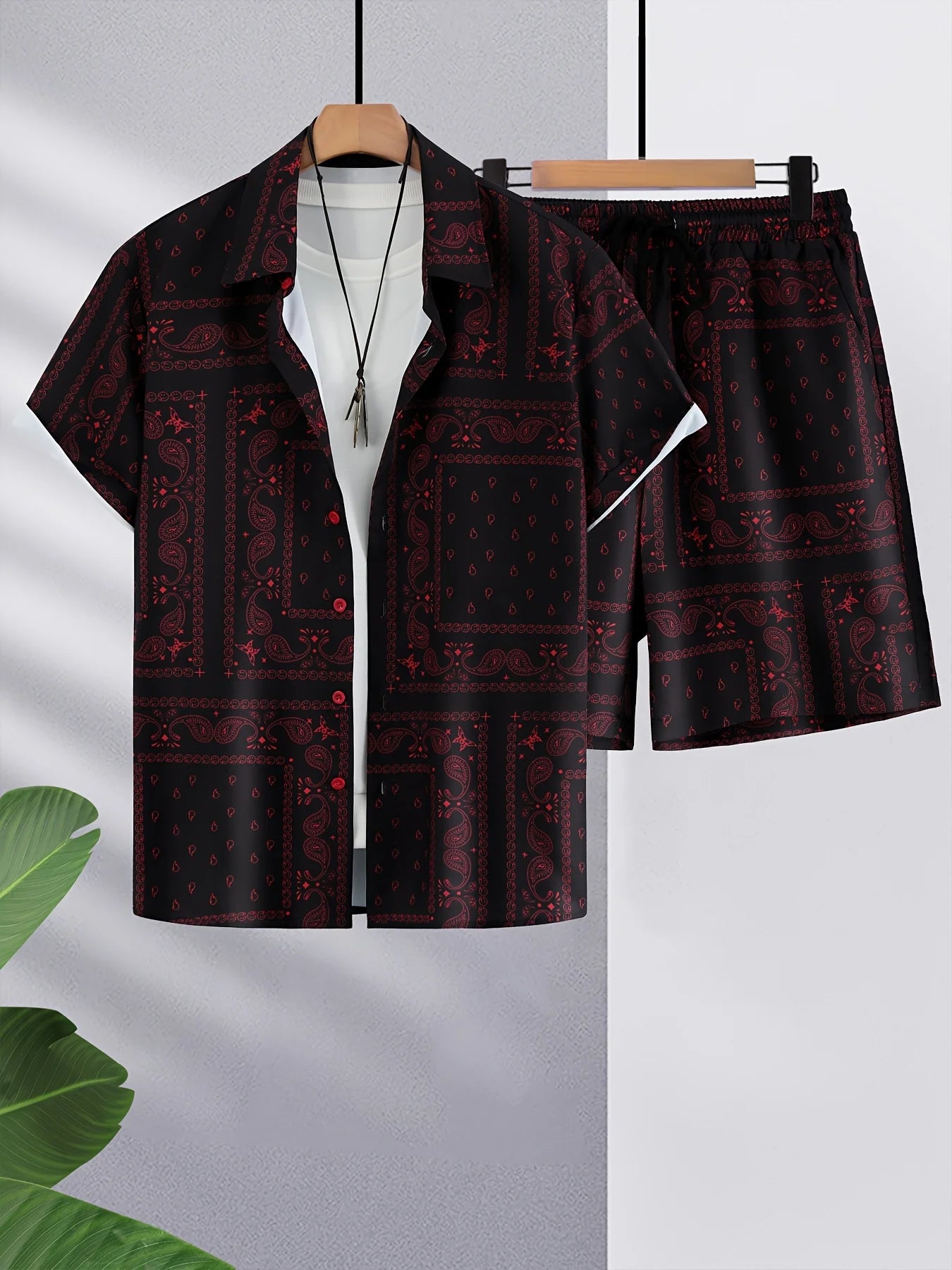 Red and black patterned shirt and shorts set on hangers against a light gray background.