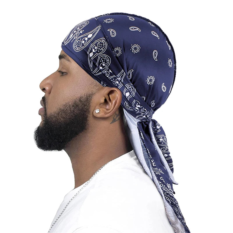 Man wearing a navy blue bandana silky satin soft durag with white paisley bandanna patterns on a white background