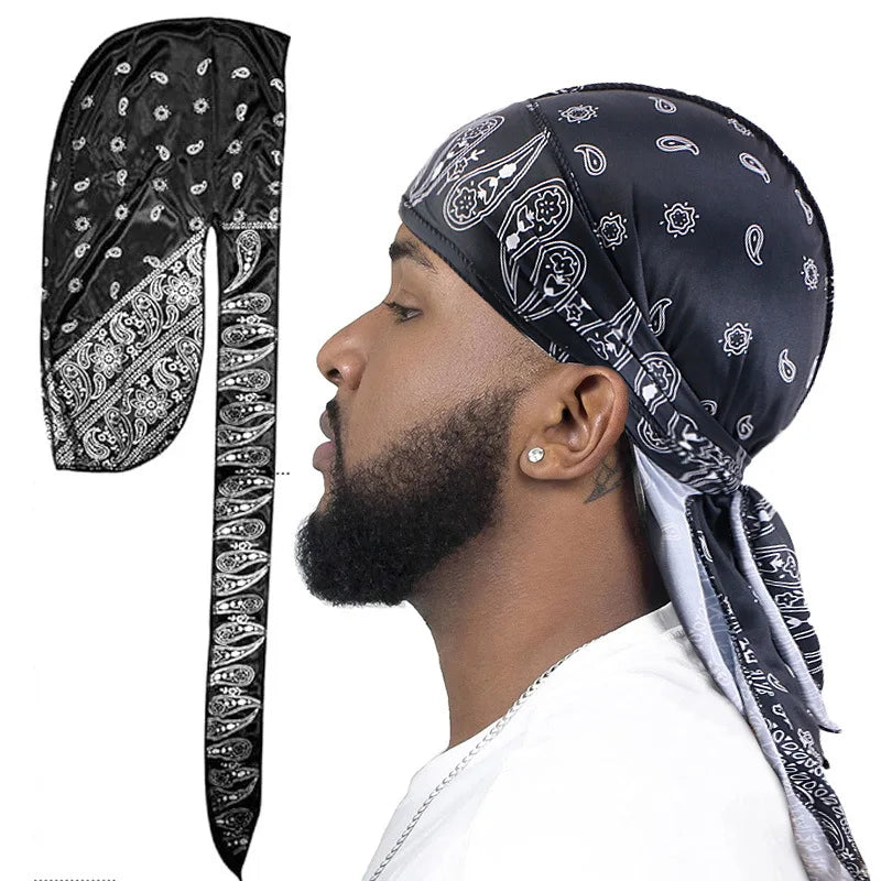 Man wearing a black bandana paisley pattern durag with white pattern on black over a white background