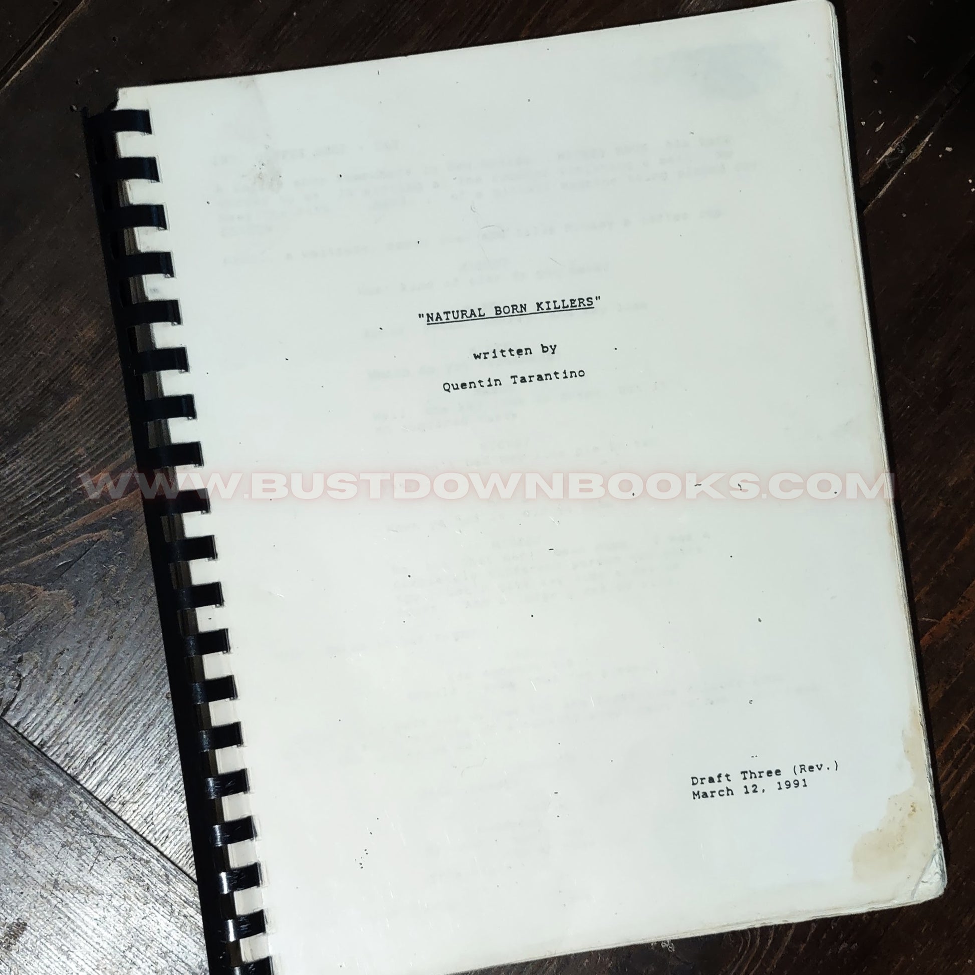 Script book titled 'Natural Born Killers' by Quentin Tarantino on a wooden surface.