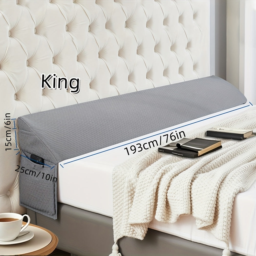 Grey bed wedge pillow with dimensions labeled on a bed against a tufted headboard.