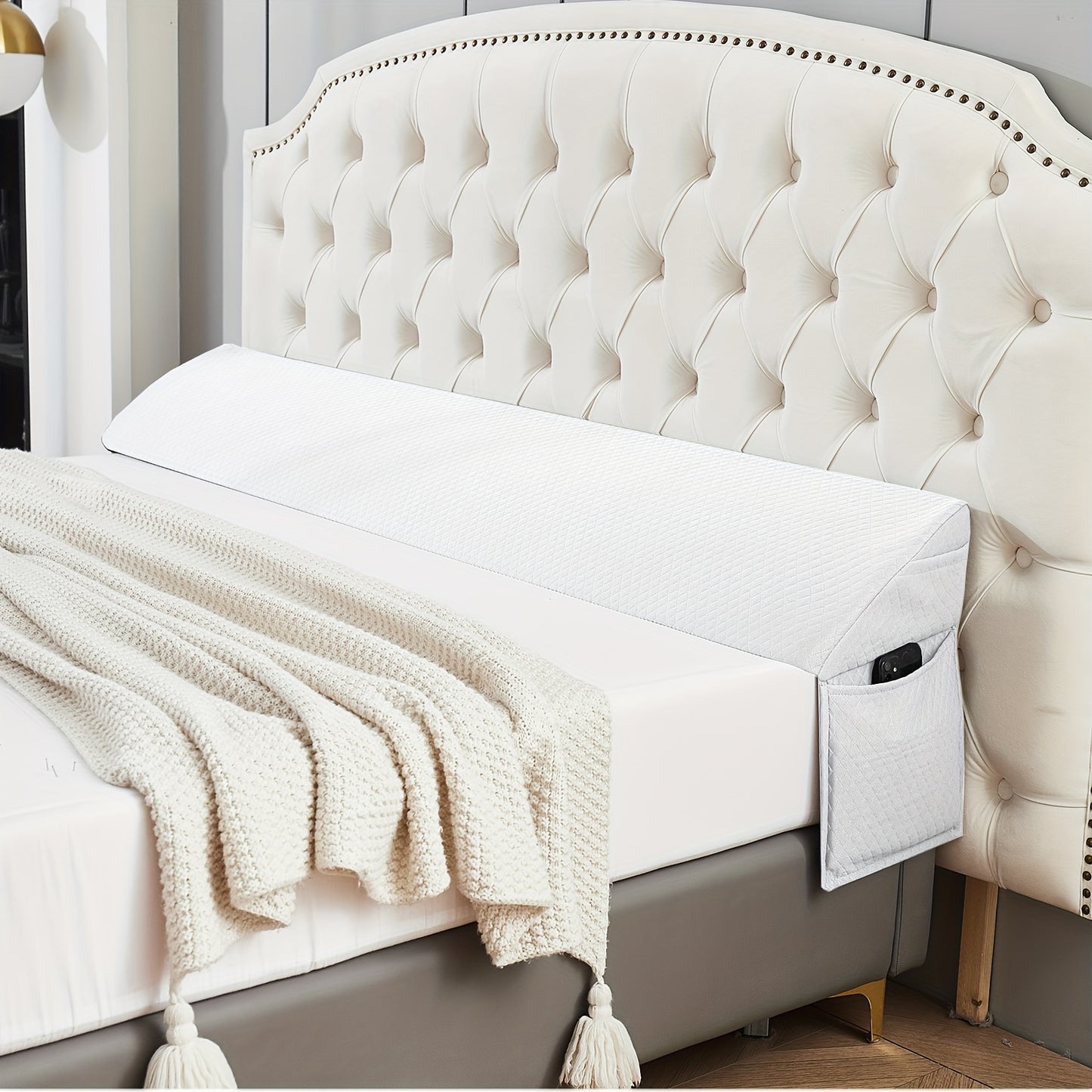 Bed with tufted headboard and white bedding, featuring a safety rail.