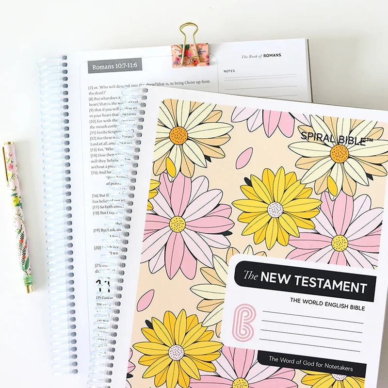 Spiral-bound Bible with floral cover and New Testament section on a white background