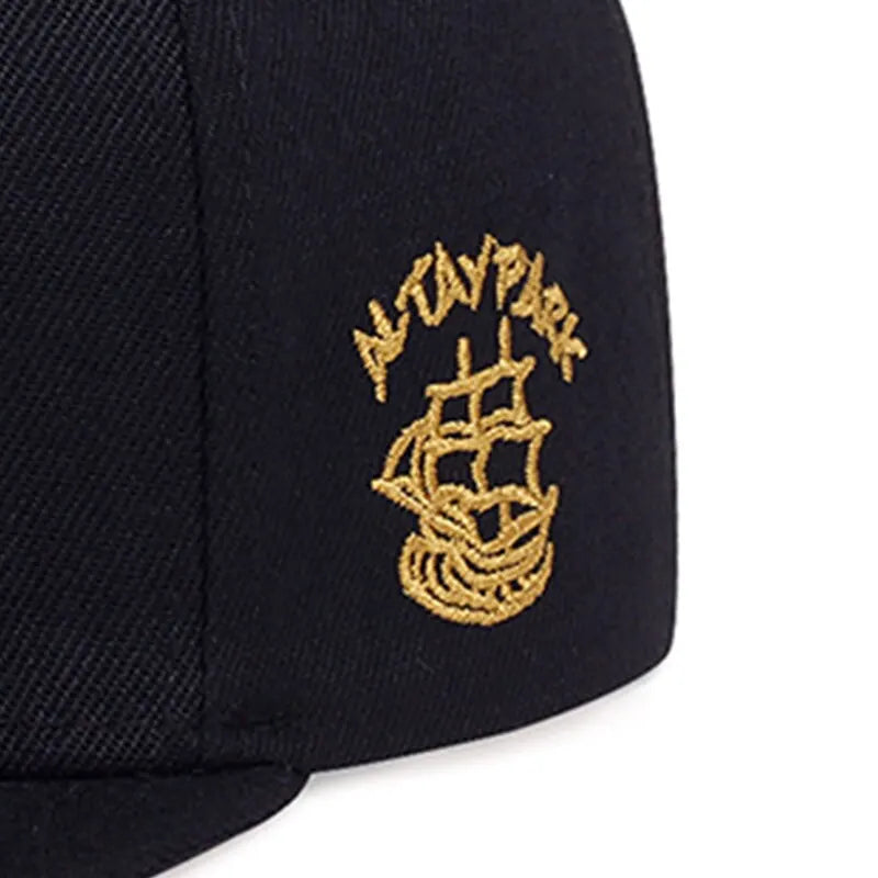 Black cap with gold embroidered design on a white background