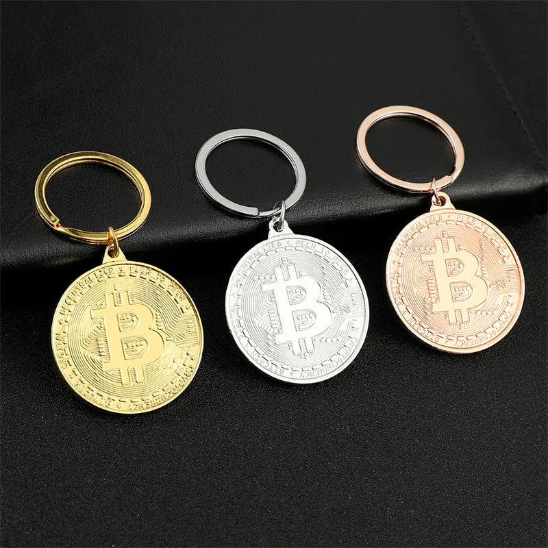 Three Bitcoin-themed keychains in gold, silver, and rose gold on a black background