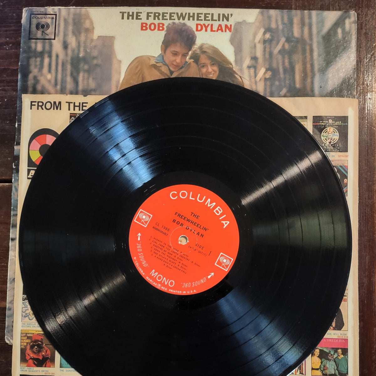Image of The Freewheelin' Bob Dylan Vinyl Record featuring the full front cover with the paper insert and wax record displaying the side one of the album.