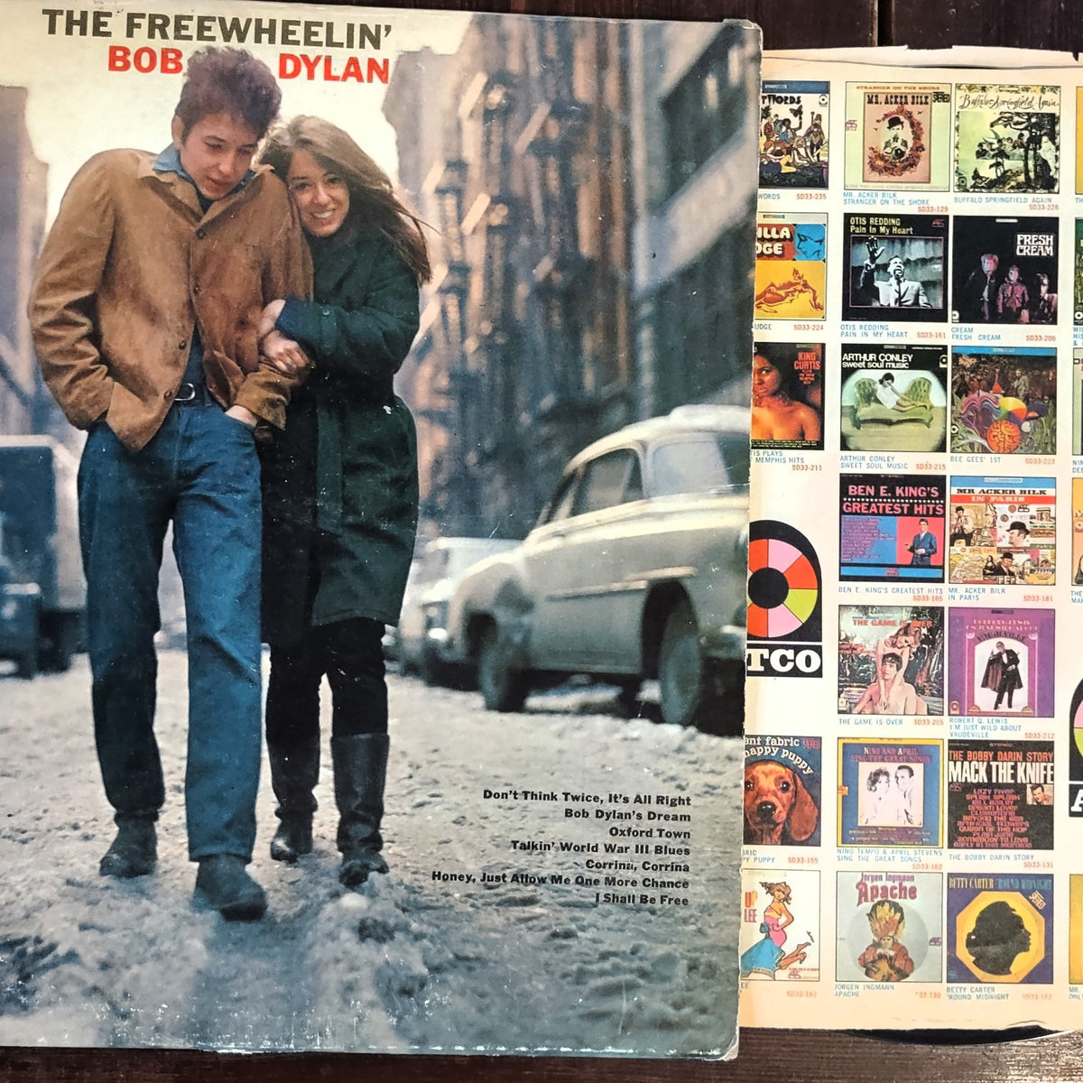 Image of The Freewheelin' Bob Dylan Vinyl Record featuring the front cover with the paper insert, close-up on woodgrain background.