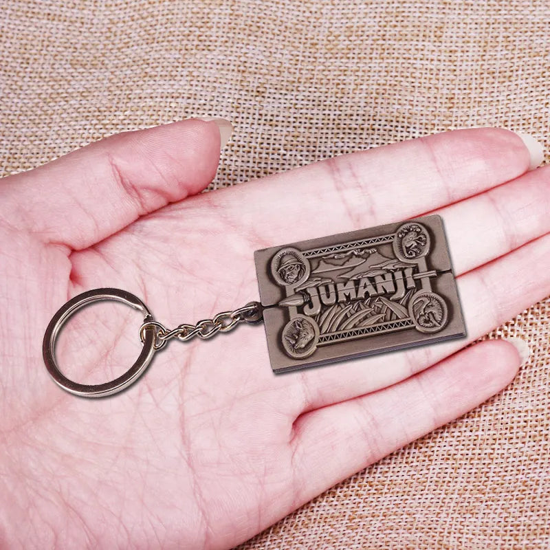 Bronze 'Jumanji' keychain held in a hand against a textured beige background