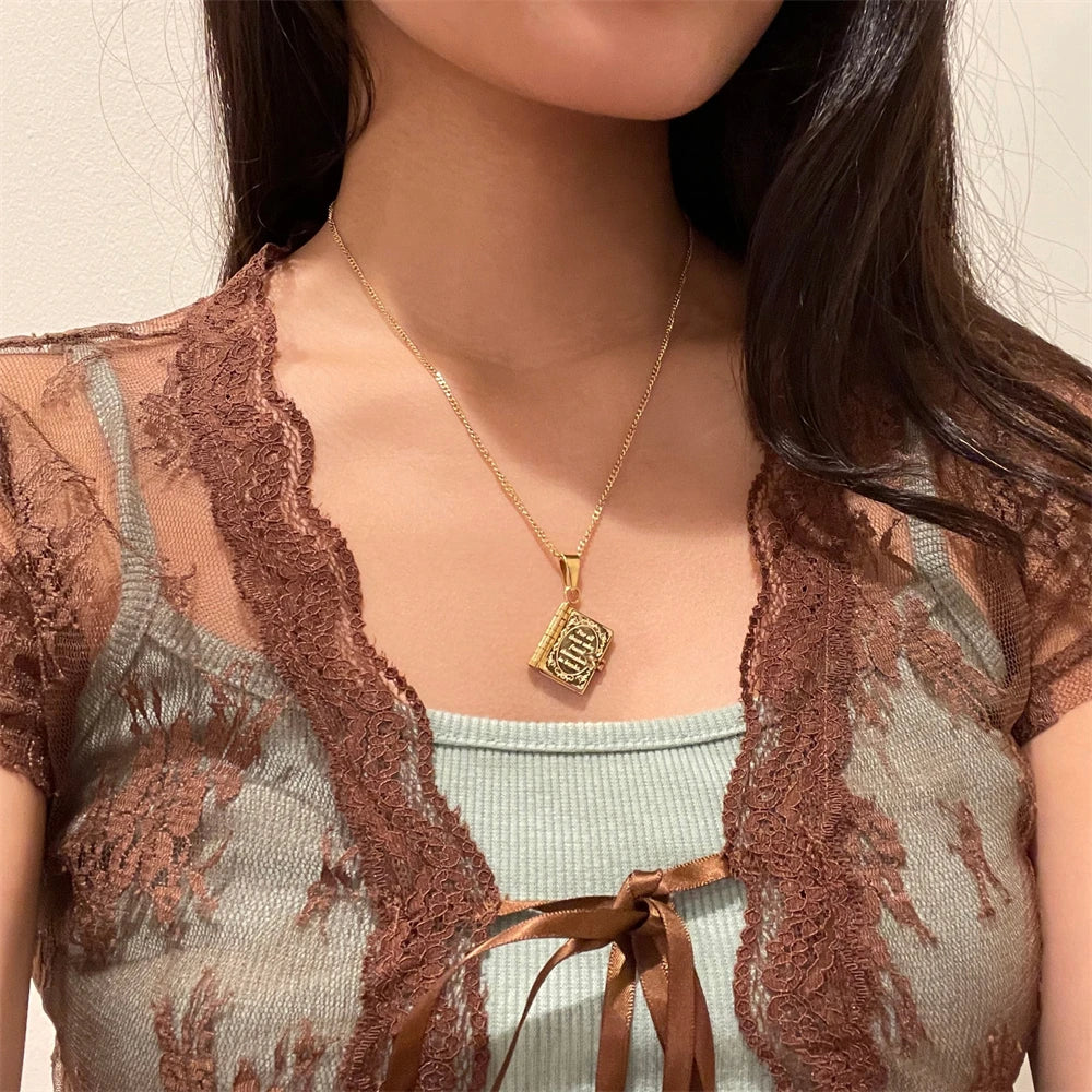 Gold necklace with a pendant worn by a person against a neutral background