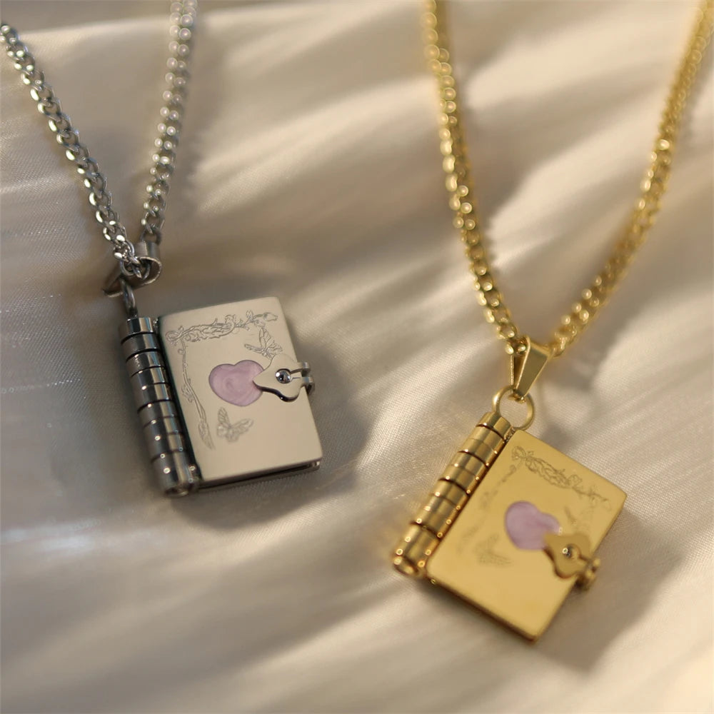 Two necklaces with book-shaped pendants on a light fabric background