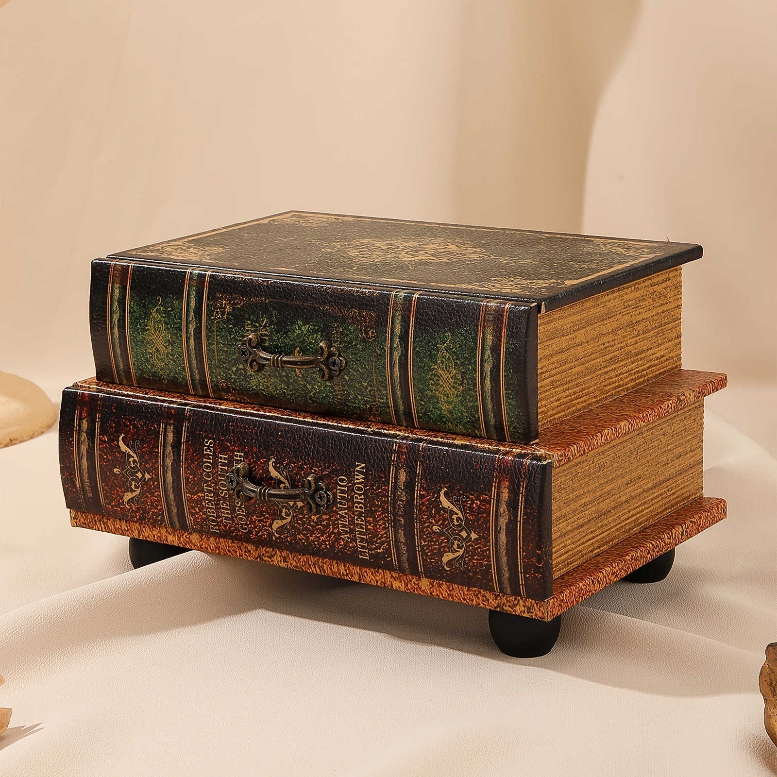 Two decorative book-shaped boxes stacked on a beige background