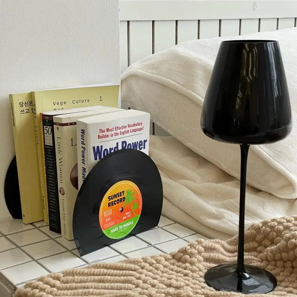 Lamp next to a bed  and small book collection using the vinyl record bookends.