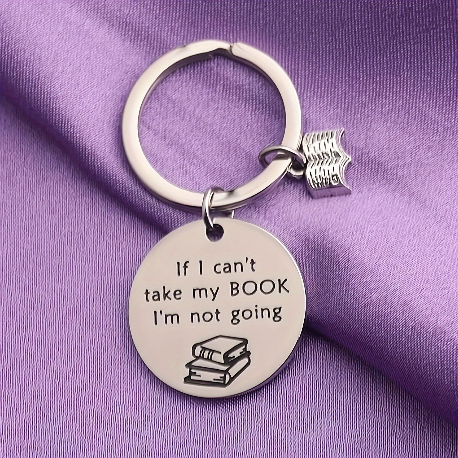 Keychain with engraved text and book illustration on a purple fabric background