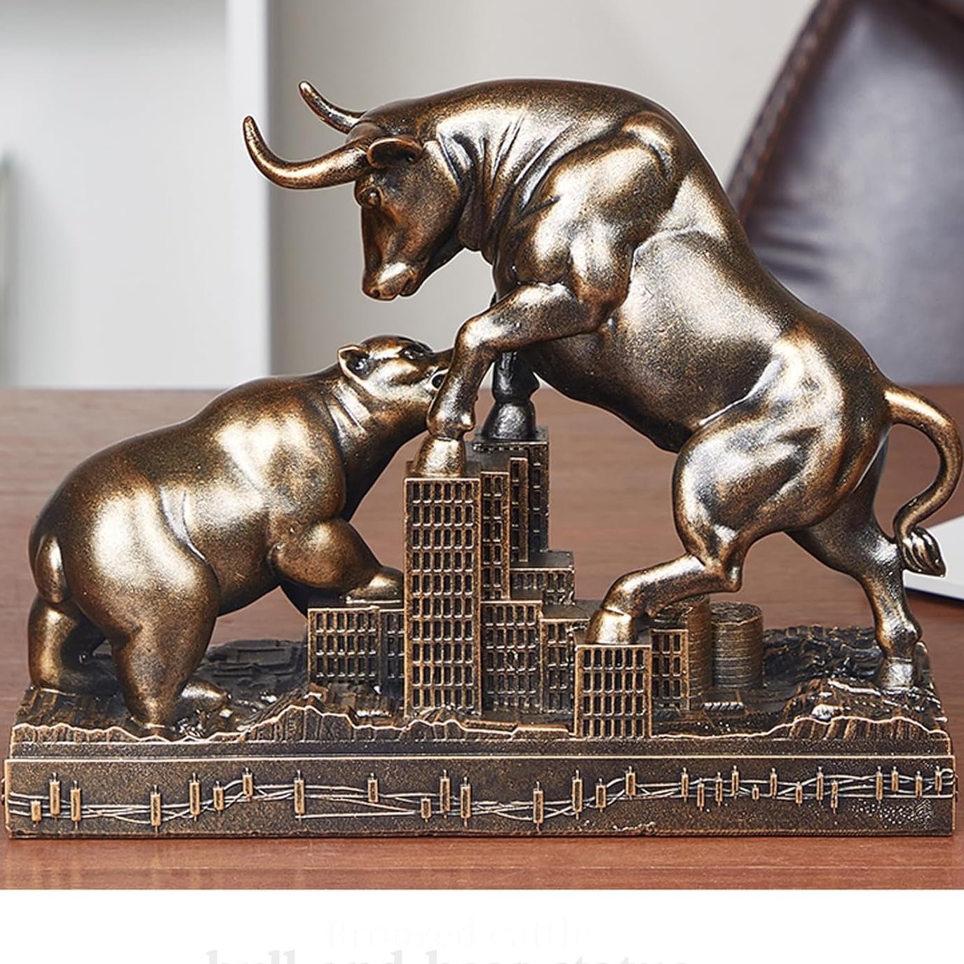 Bronze bull and bear financial sculpture on a cityscape base, displayed on a wooden surface.