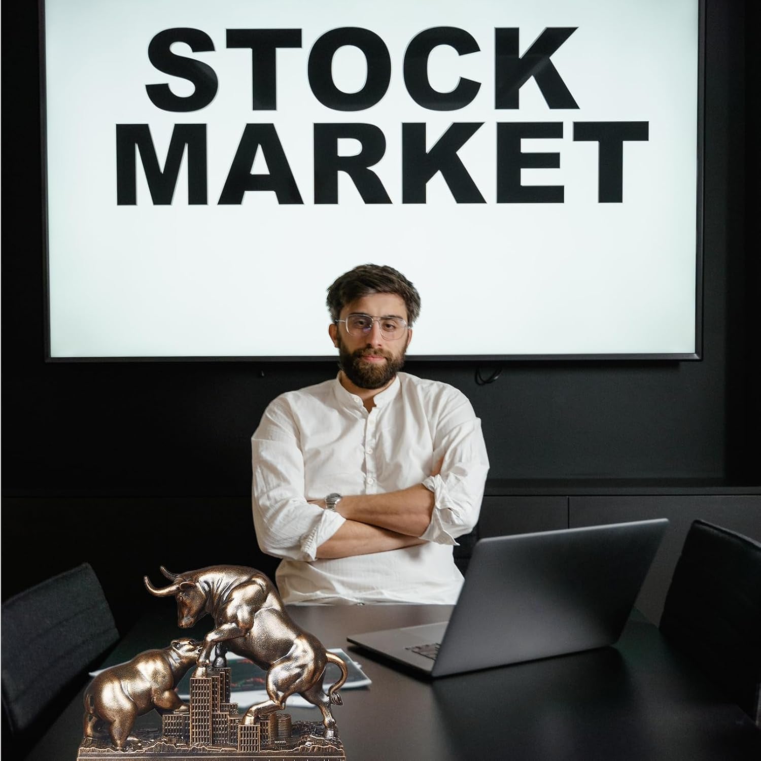 Man at Stock Market desk with bull and bear desk with bull and bear statue on minimalist work desk.