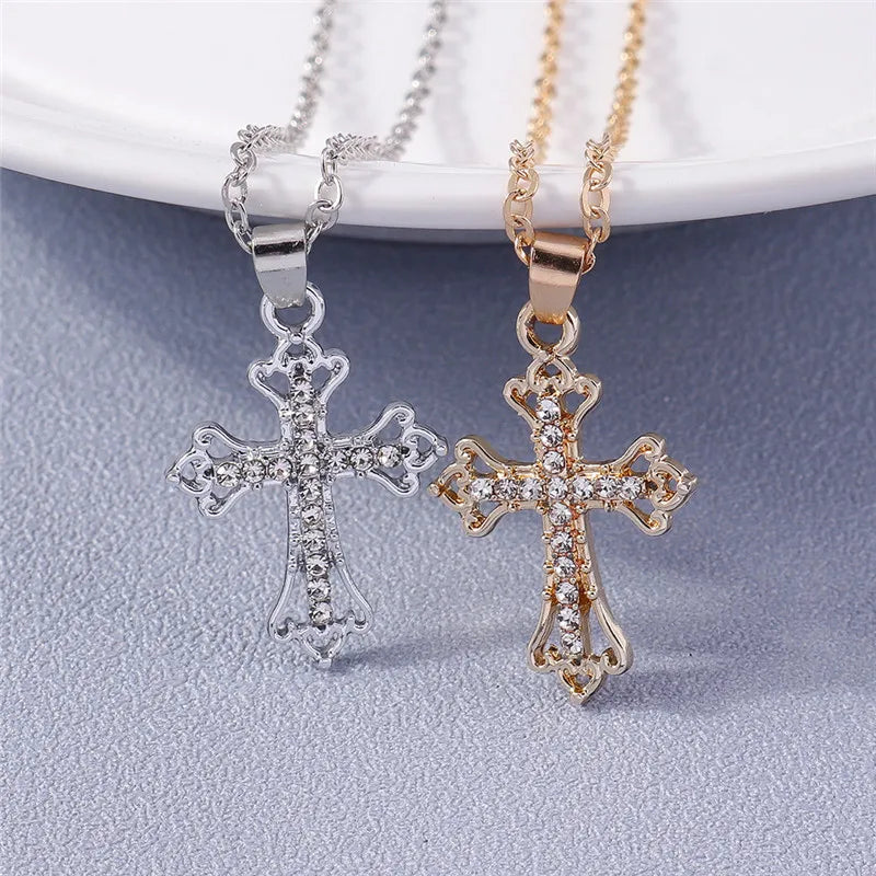 Two cross-shaped pendants, one silver and one rose gold, on a light gray background.
