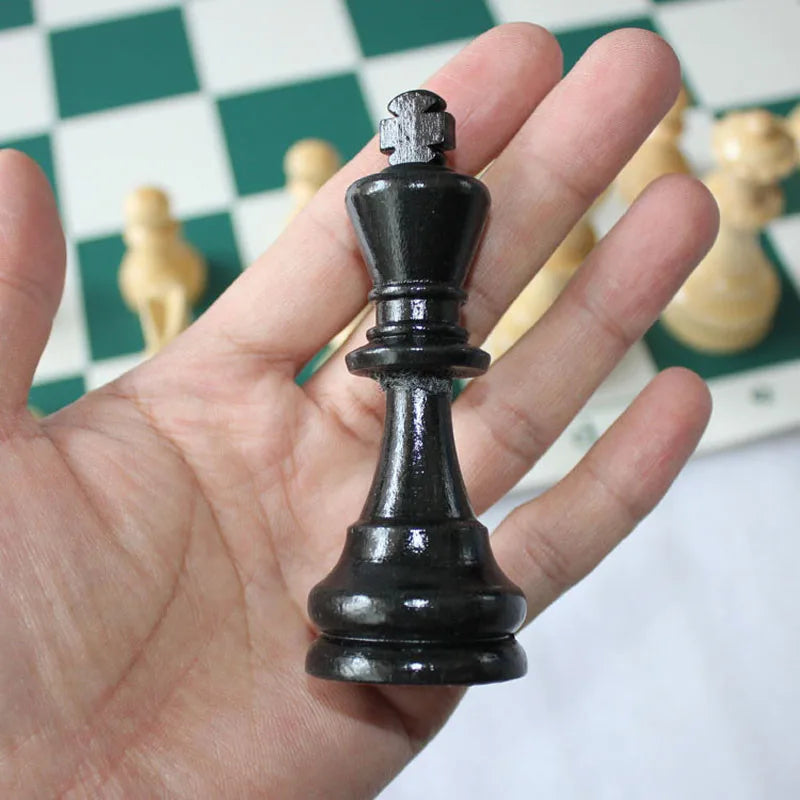 Black chess piece held in a hand with a chessboard in the background