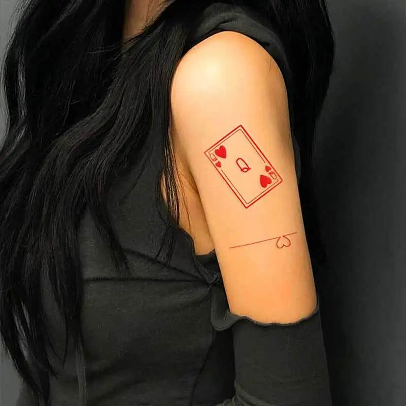 Person with a tattoo of a playing card design on their arm against a dark background