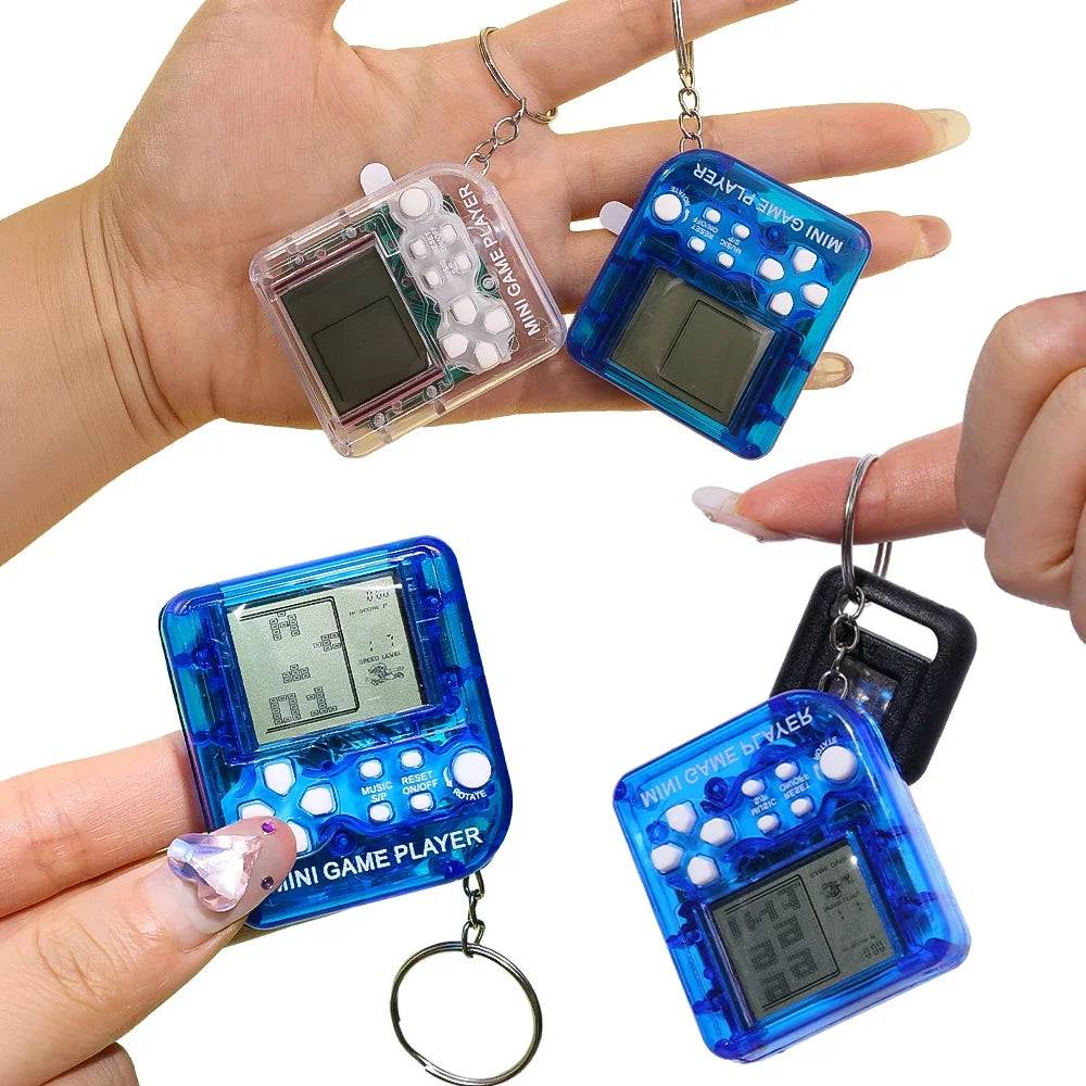 Hand holding blue mini game player keychains with screens and buttons, on a white background