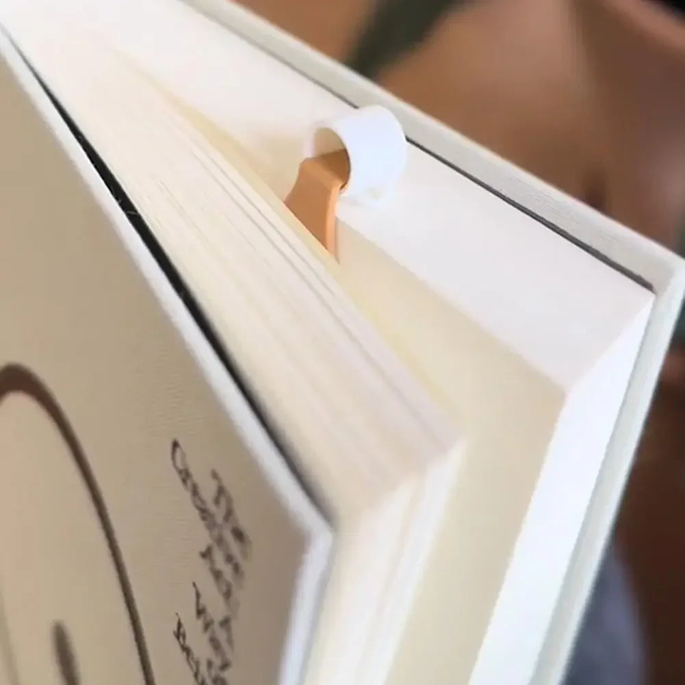 White book with a spilling coffee cup cartoon bookmark inside, marking a page.