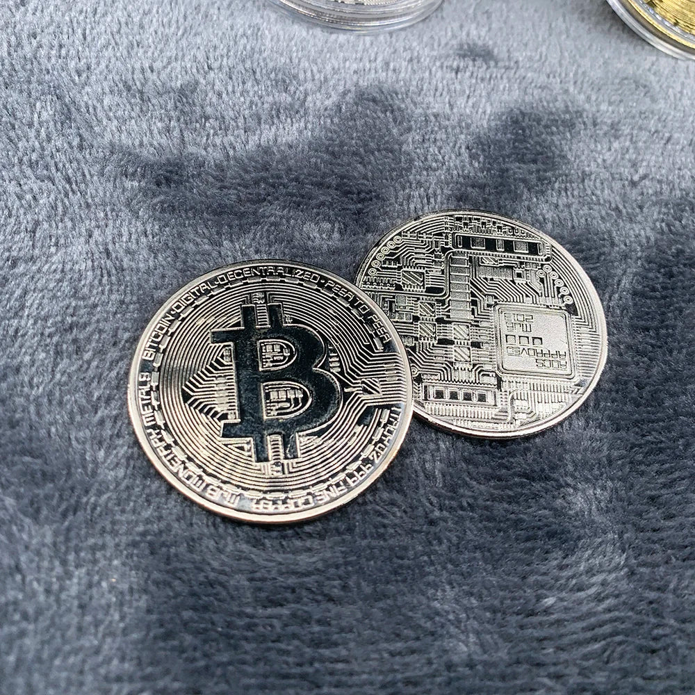 Two Bitcoin commemorative coins on a textured surface