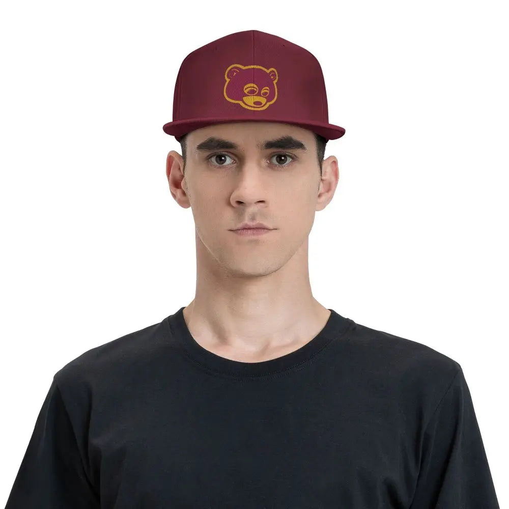 Model wearing Maroon 'College Dropout Kanye Snapback: Bear Mascot OSFA 9-Colorways' cap with yellow bear logo on a white background front logo hat view.