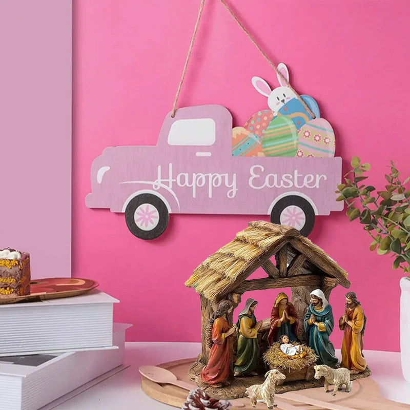 Decorative sign with a pink truck and Easter eggs against a pink wall, with a nativity scene below.