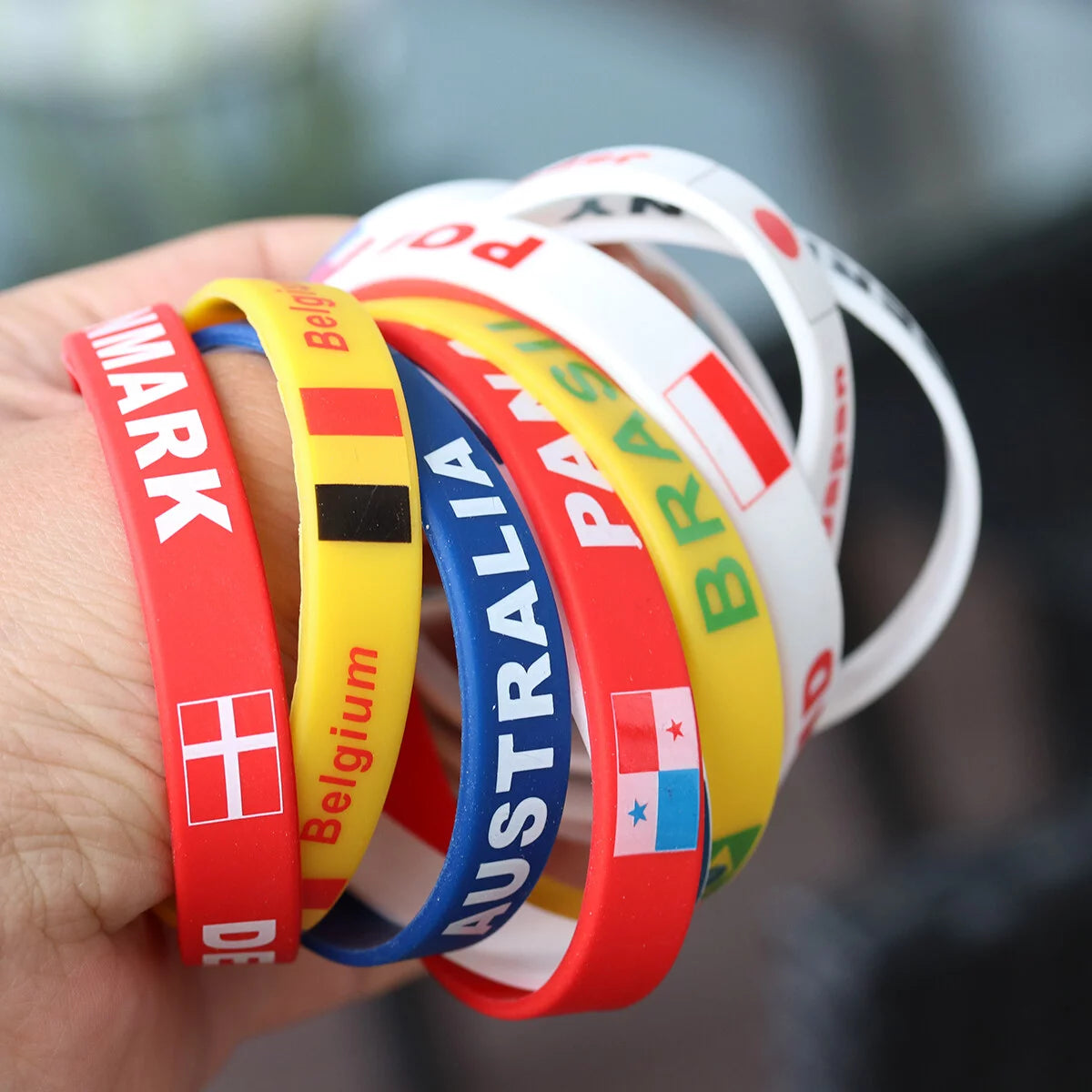 Hand holding up a bundle of silicone bracelets with the 'Croatia' bracelet featured with others.