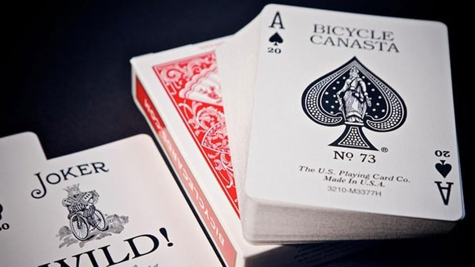 Bicycle playing cards with a Joker card and Ace of Spades on a dark background