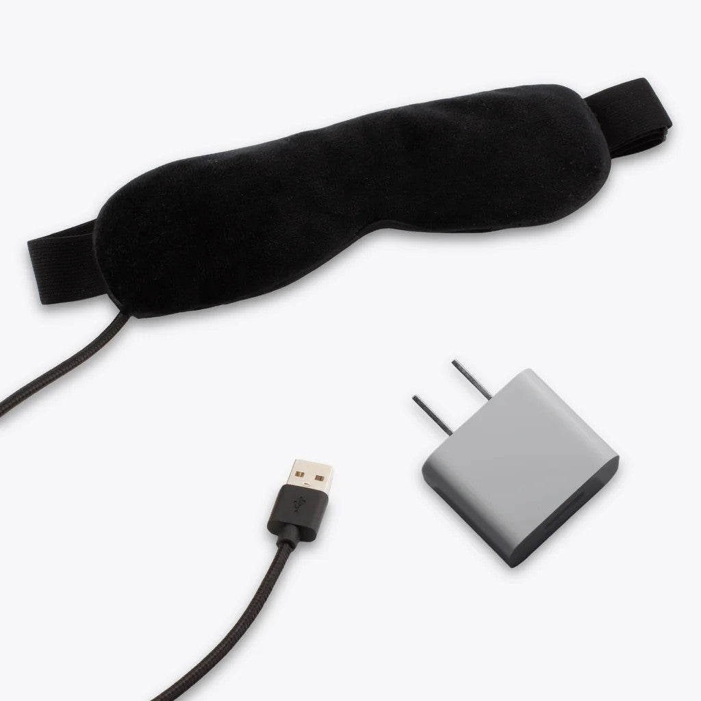 Black sleep mask, USB cable, and power adapter on a white background