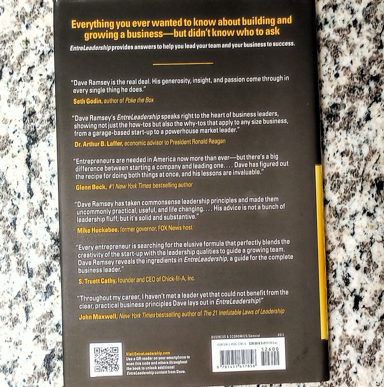 Back cover of a book with text and a QR code on a textured surface