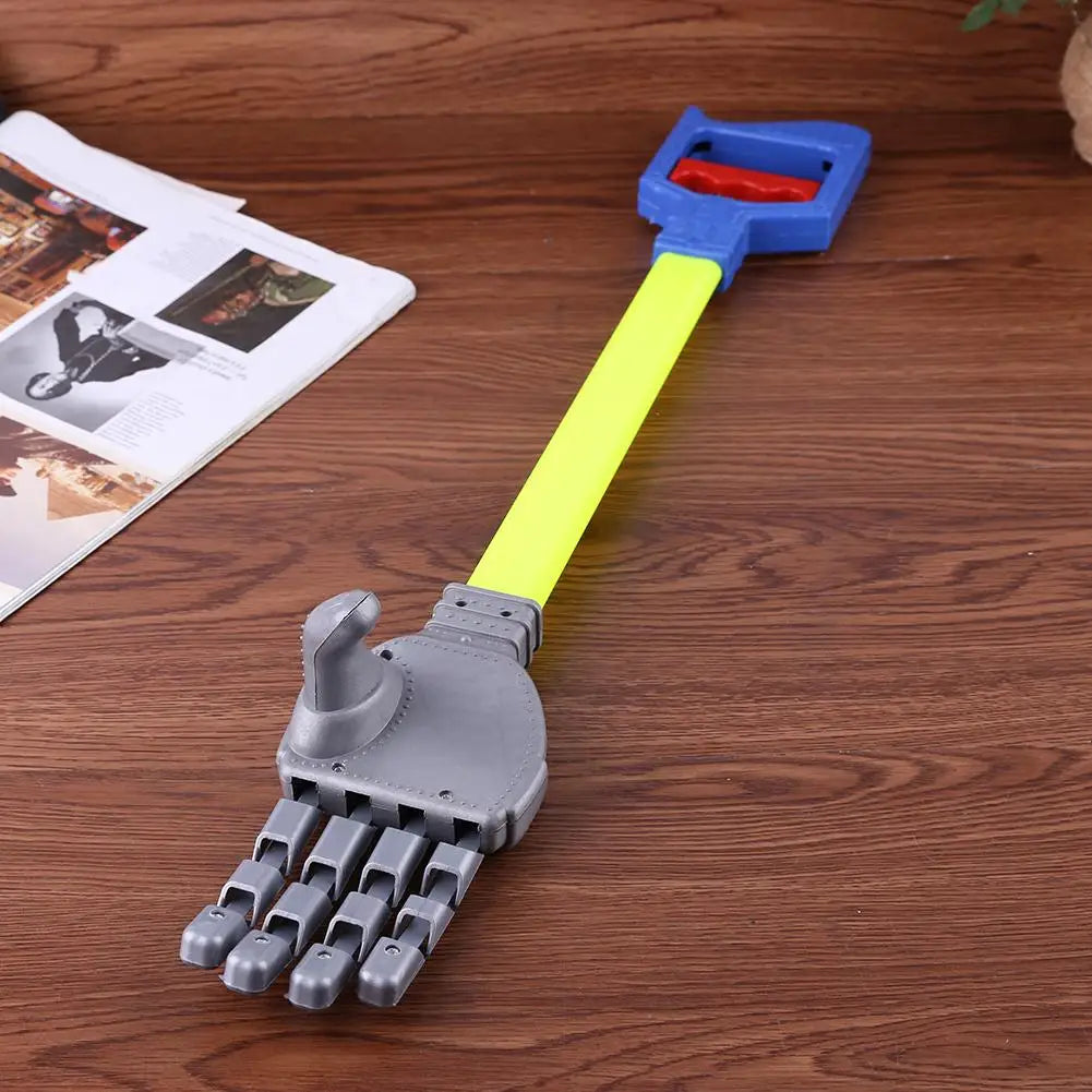 Toy-like mechanical hand with a yellow handle on a wooden surface