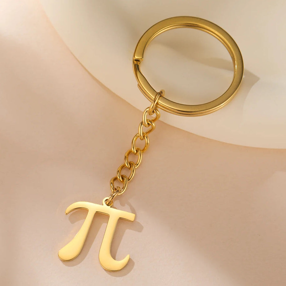 Gold keychain with pi symbol on a beige background