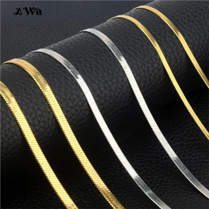 Close-up of gold and silver flat chain necklaces on a dark background.
