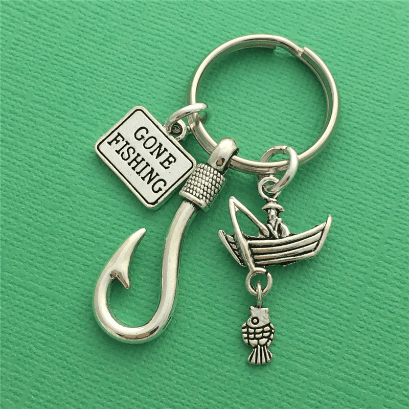 Silver fishing-themed keychain with 'Gone Fishing' sign on a green background