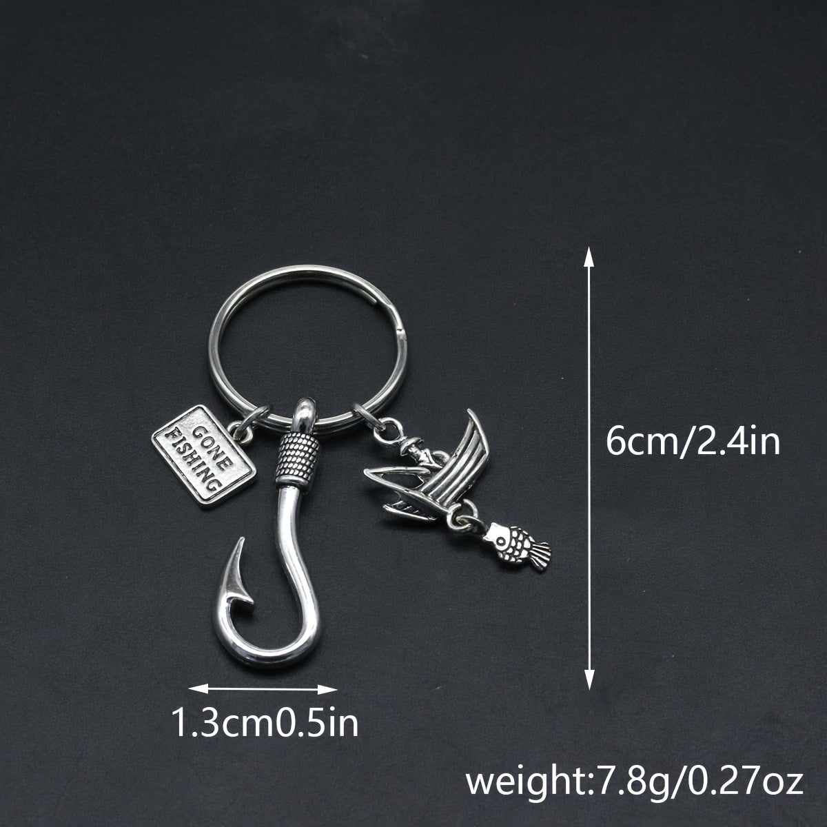 Fishing-themed keychain charm with measurements on a dark background