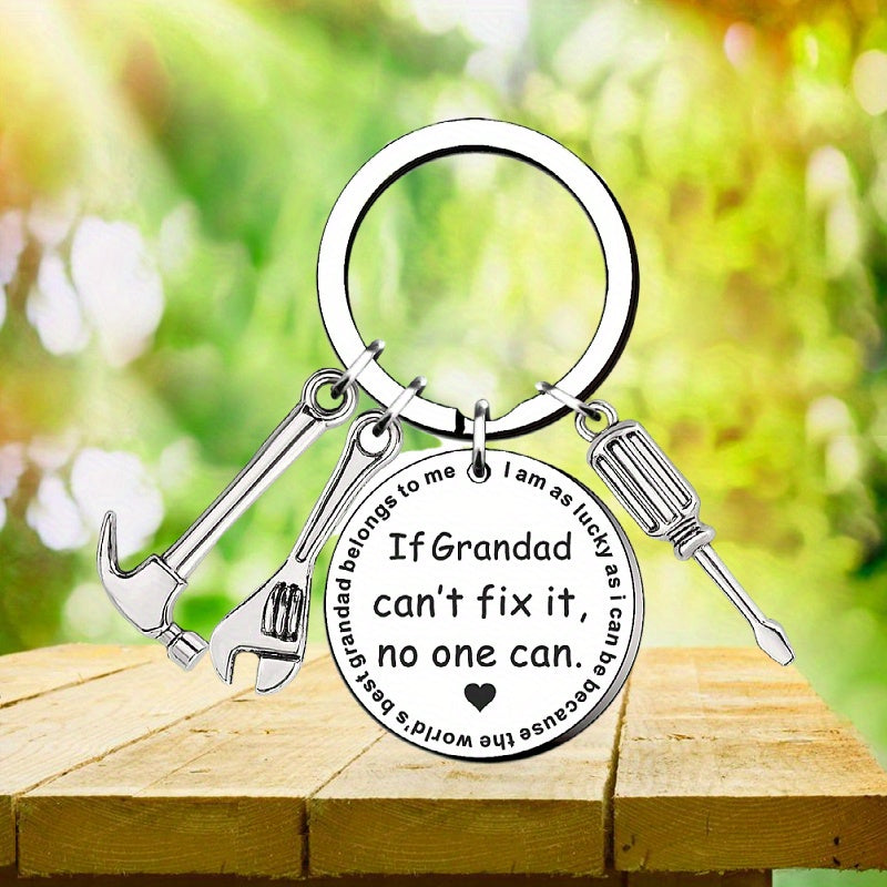 Keychain with tools and engraved message on a wooden surface with a blurred green background