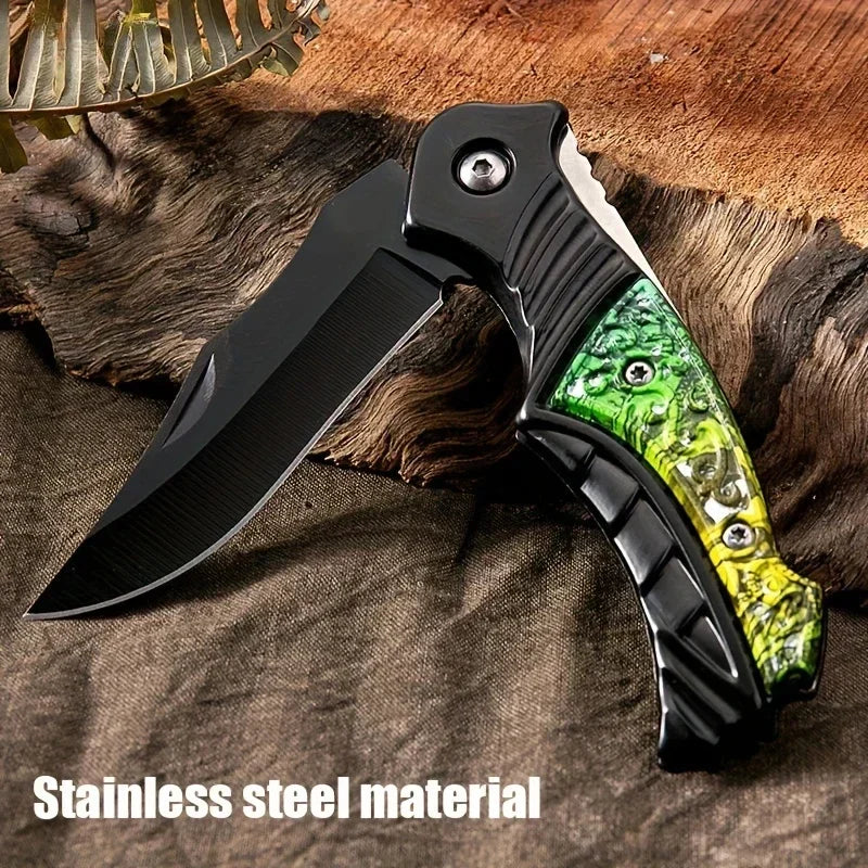 Folding knife with green and black handle on a wooden surface, labeled 'Stainless steel material'.