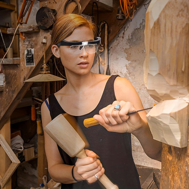Person in a workshop holding a sander and a tool, wearing safety wearable head lamp and magnifying glass.