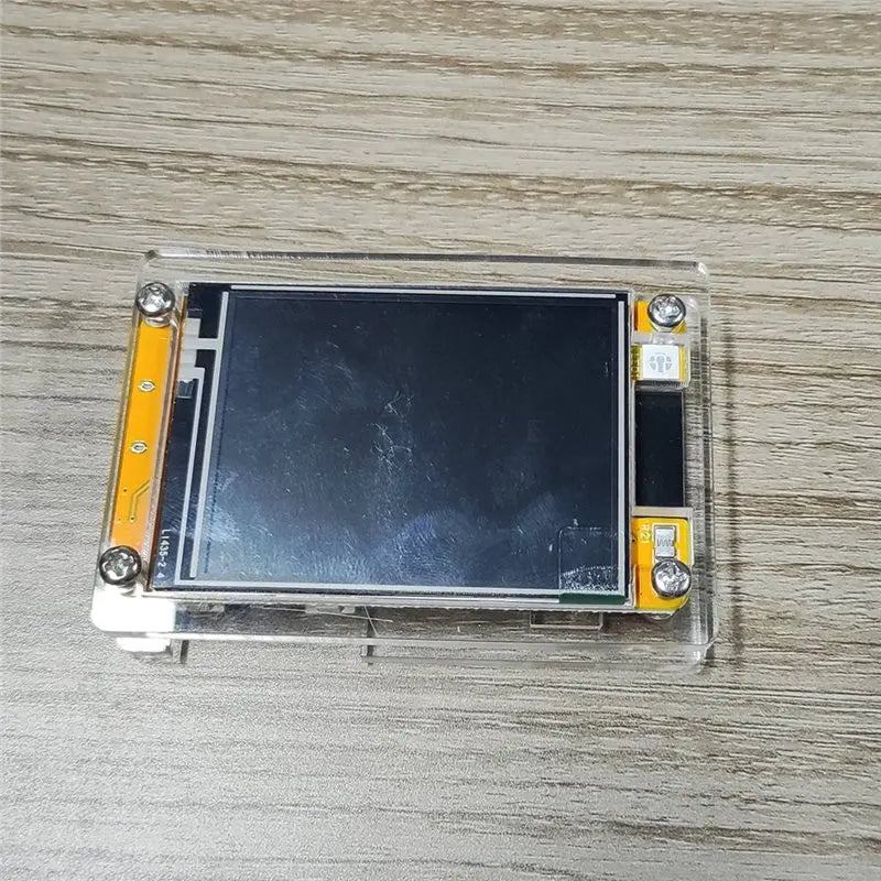 Small screen NerdMiner display module with yellow and silver frame on a wooden surface