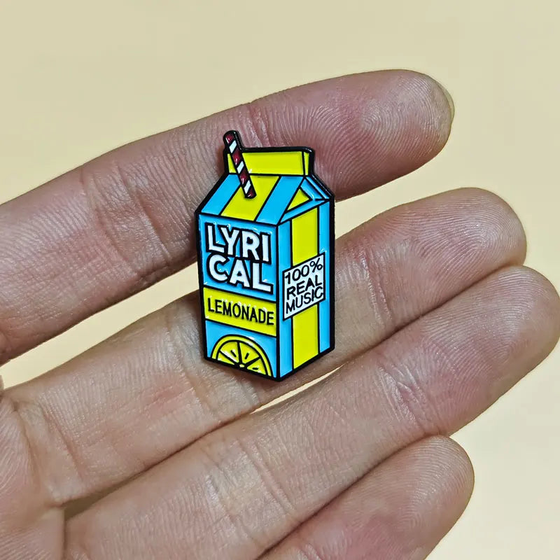 Juice WRLD pin shaped like a lemonade box carton with 'LYRICAL LEMONADE' text held between fingers.