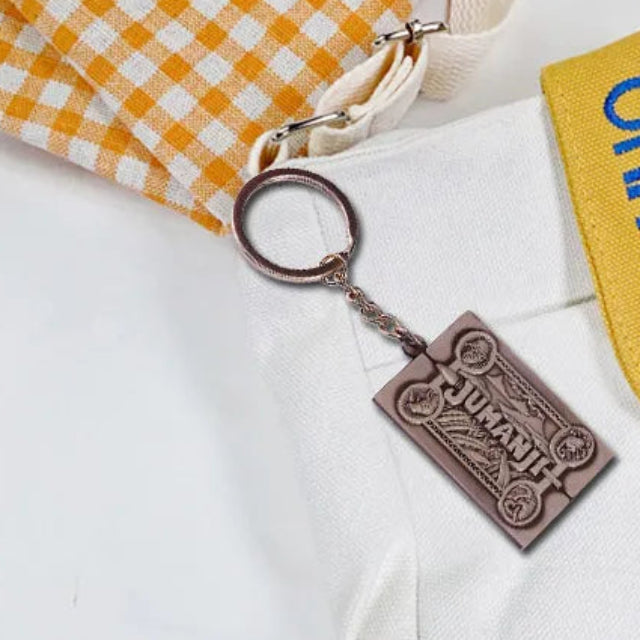 Jumanji movie keychain placed over linens and contrasting copper/bronze 'Jumanji' keychain color.