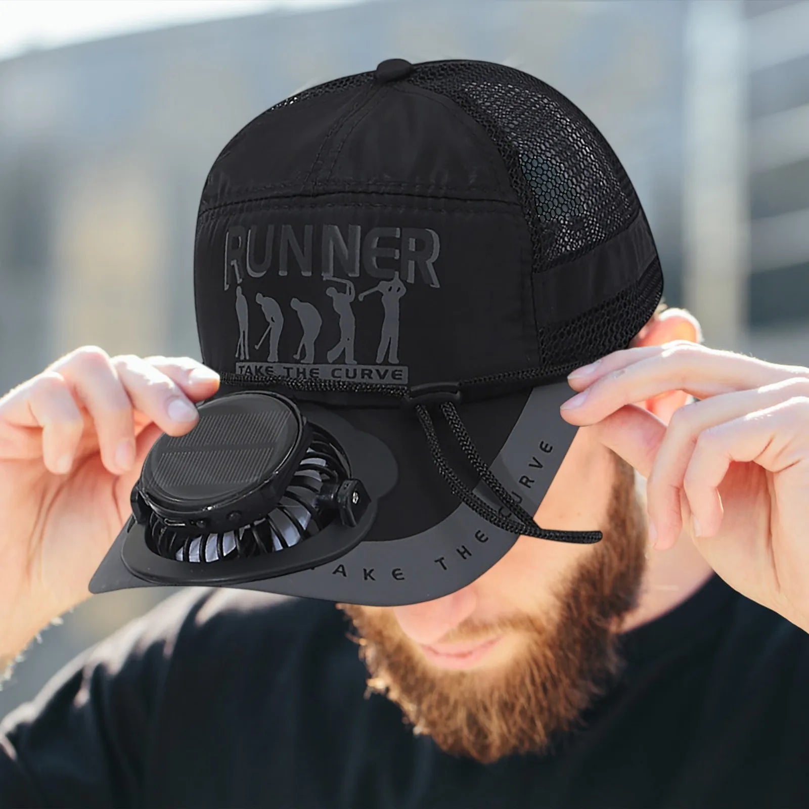 Man wearing the black keep cool fan brim baseball cap and pulling down bill to display the cap being worn.