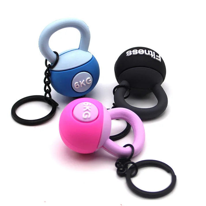 Three small kettlebell-shaped weights with keychains on a white background