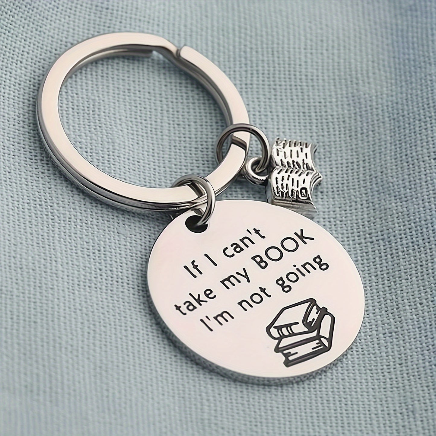 Keychain with 'If I can't take my BOOK, I'm not going' text and book emoji on a light blue background