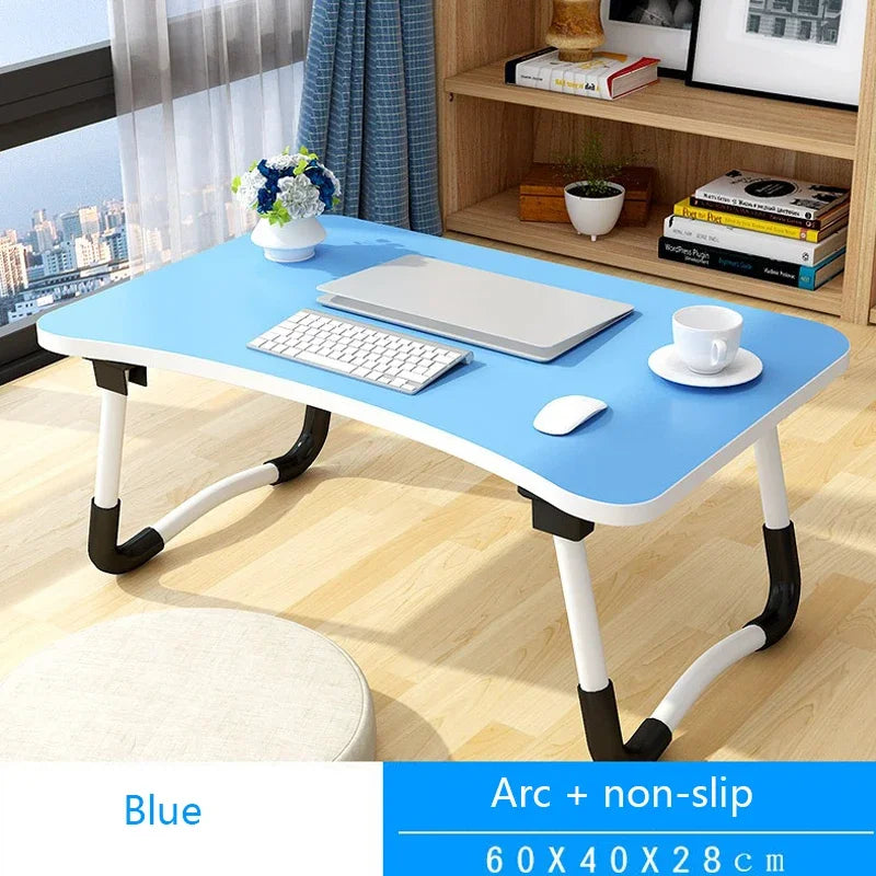 Blue adjustable desk with computer setup in a room with a cityscape view.