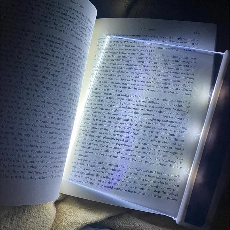 Open book with a light shining on it, held by a hand.